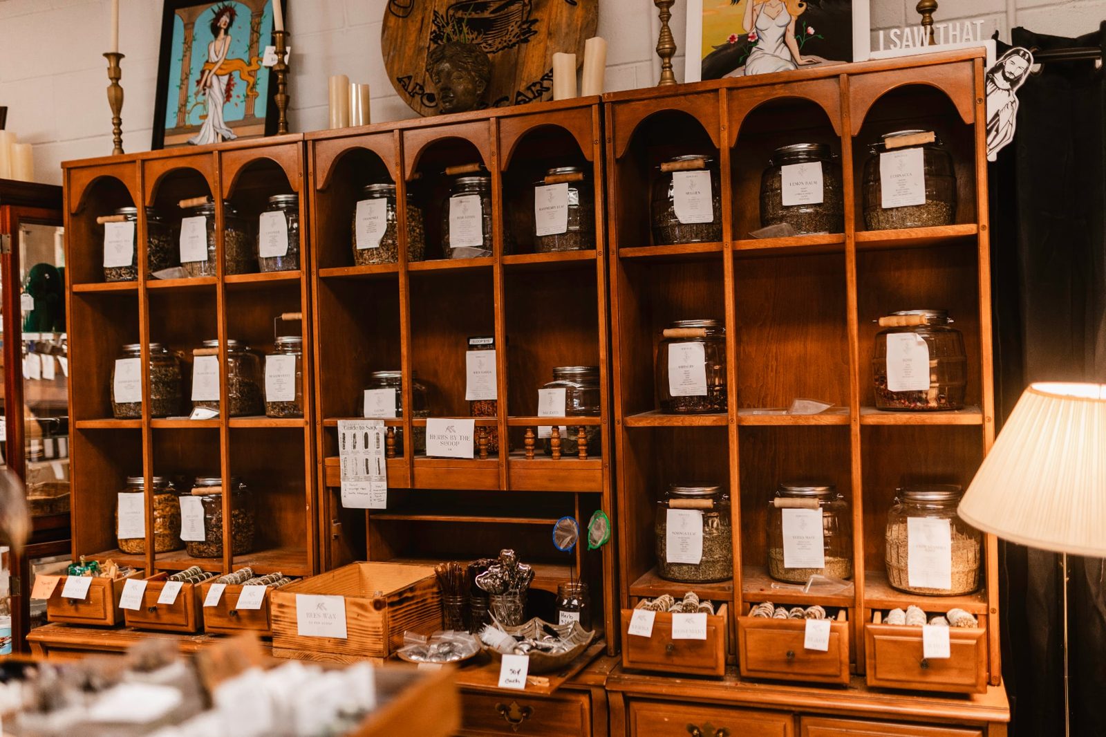 Inside Clary & Sage Apothecary — wooden shelves lined with herb jars, tinctures, and a warm lamp
